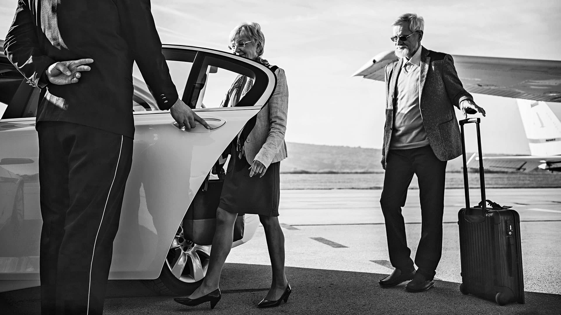 Chauffeur assisting airport passengers with luggage